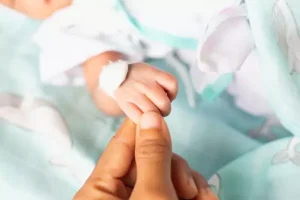 mãe segurando mão de bebê prematuro