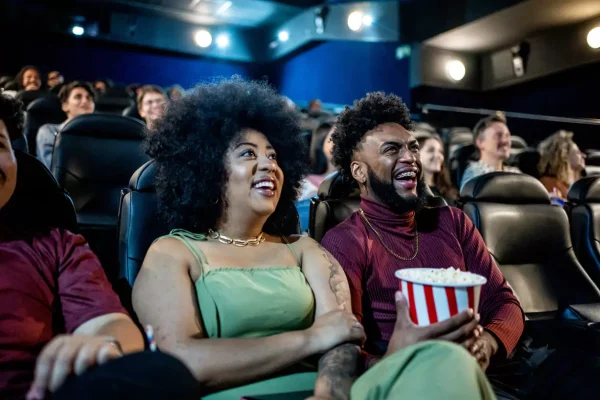 casal sorrindo dentro de sessão de cinema