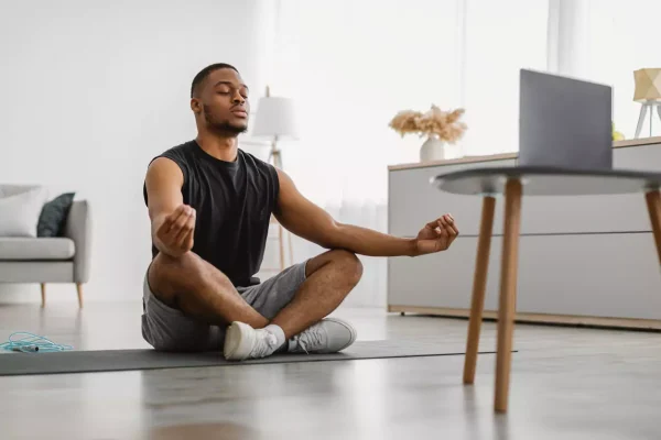 homem negro meditando na sala de sua casa