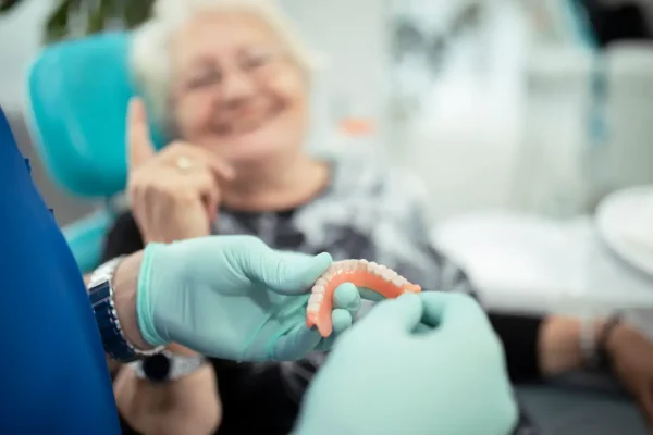 Dentista preparando prótese dentária de paciente idosa